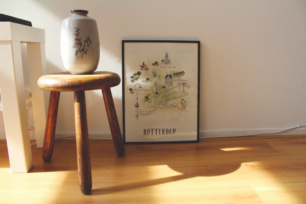 white vase on brown wooden stool near Rotterdam painting on the floor